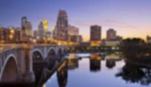 Blurry city skyline with bridge at sunset.