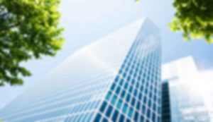 Blurred skyscraper with trees in foreground.