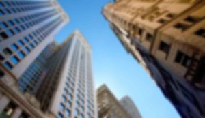 Looking up at blurred skyscrapers, clear sky.