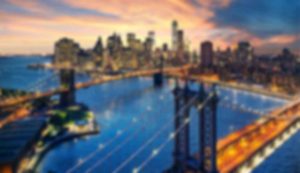 Blurry cityscape with bridge at sunset.