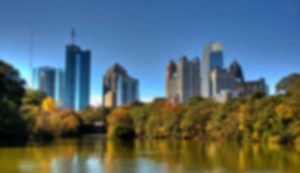 Blurry city skyline with trees and water.