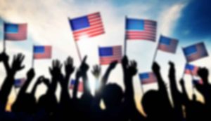 Silhouetted crowd waving American flags.