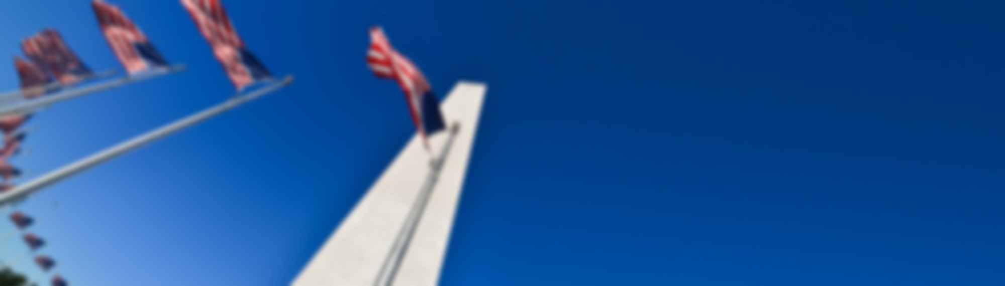Monument with flags against clear blue sky.