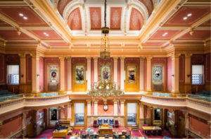 Ornate hall with grand chandelier and paintings.