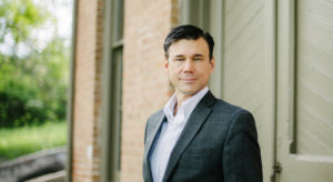 Man in suit standing outside brick building.