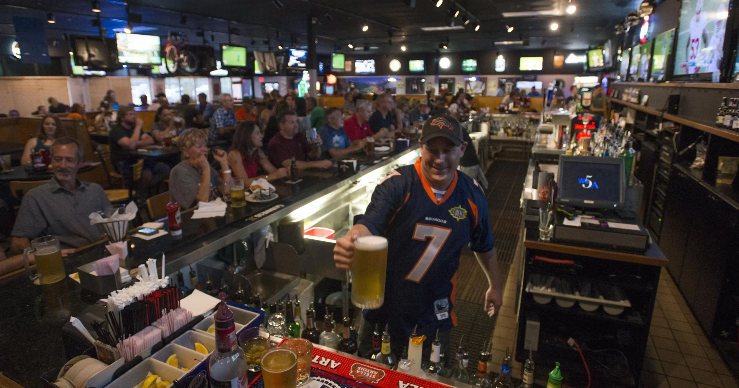 Bartender serving beer in a crowded bar.