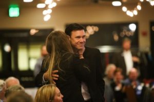 People hugging at an indoor event.