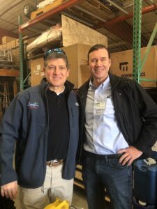 Two men smiling in a warehouse.