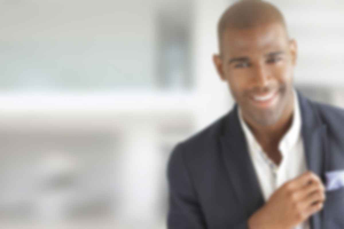 Smiling man in a suit, blurred background.